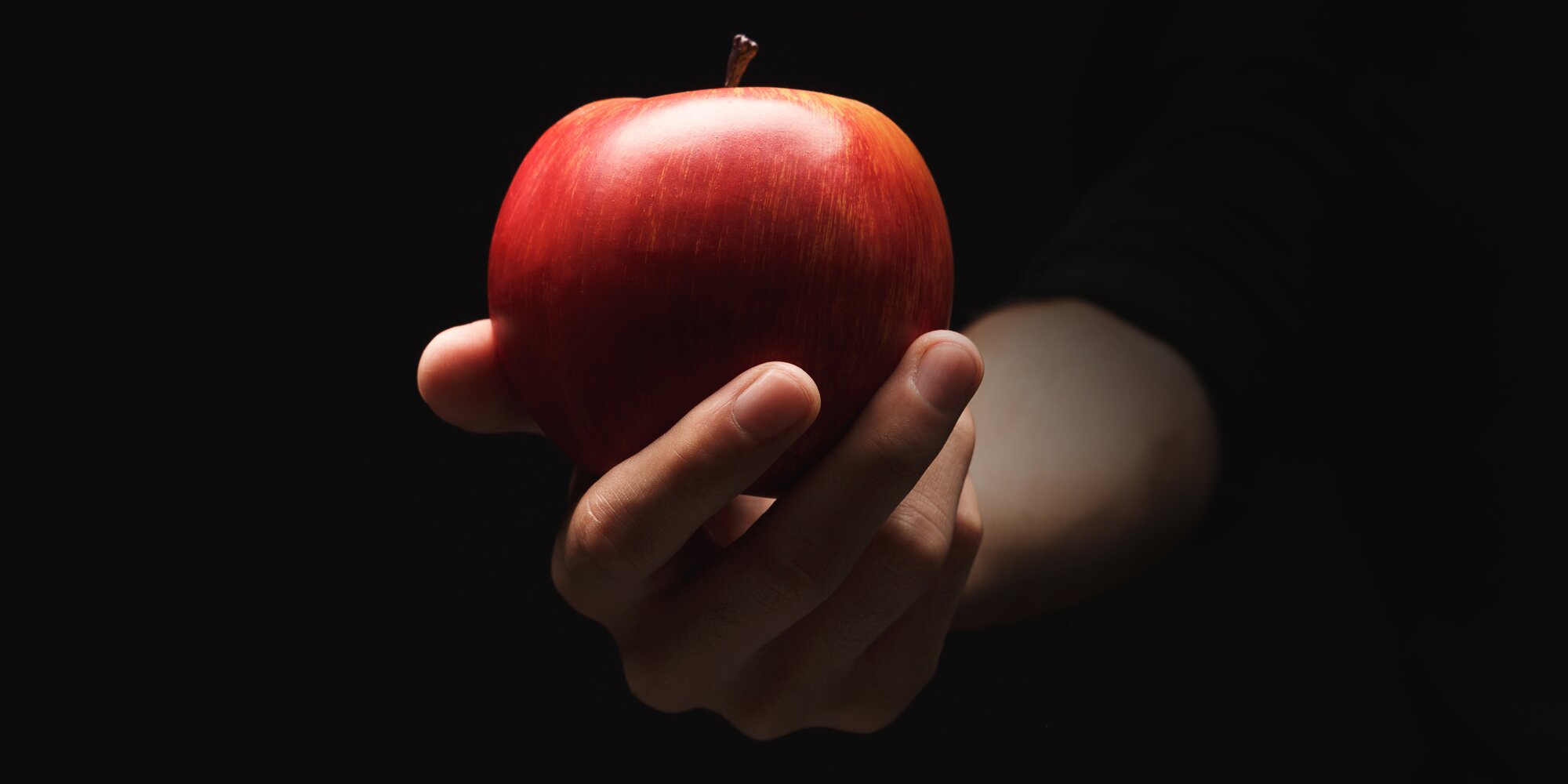 Кинуть яблоко. Яблоко в руке. Яблоко на черном фоне. Яблоко на темном фоне. Яблоко в руке на темном фоне.