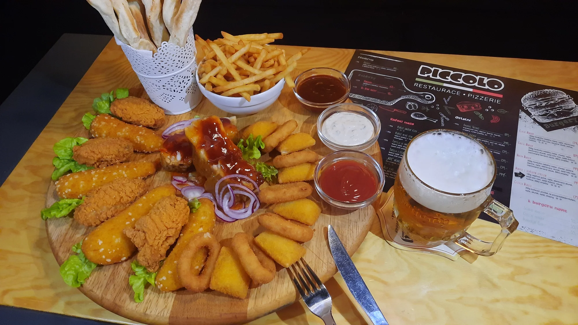 Prkno s masem a sýrem pro 2 až 4 osoby: křídla, stripsy, cibulové kroužky, žebra, hranolky a k tomu i pivo či Kofola