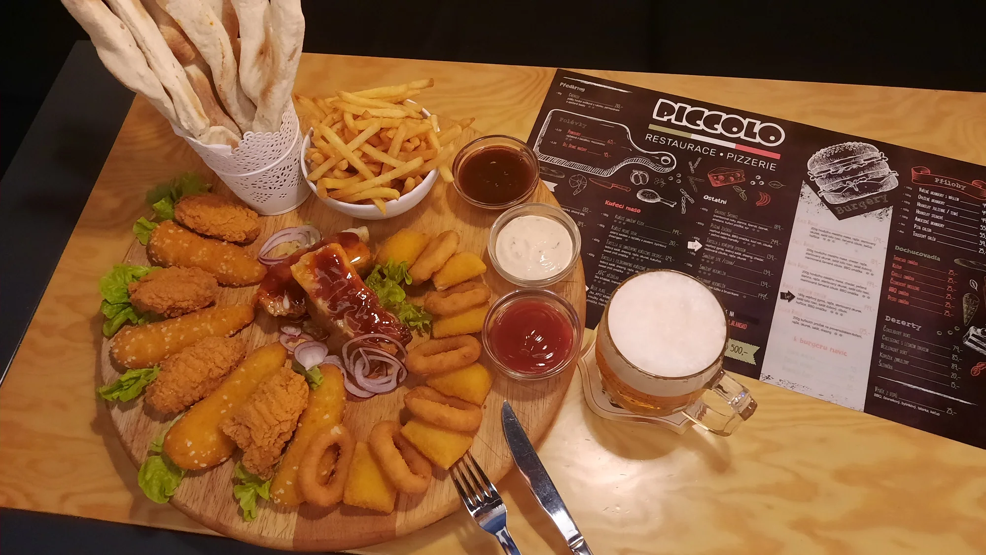 Prkno s masem a sýrem pro 2 až 4 osoby: křídla, stripsy, cibulové kroužky, žebra, hranolky a k tomu i pivo či Kofola