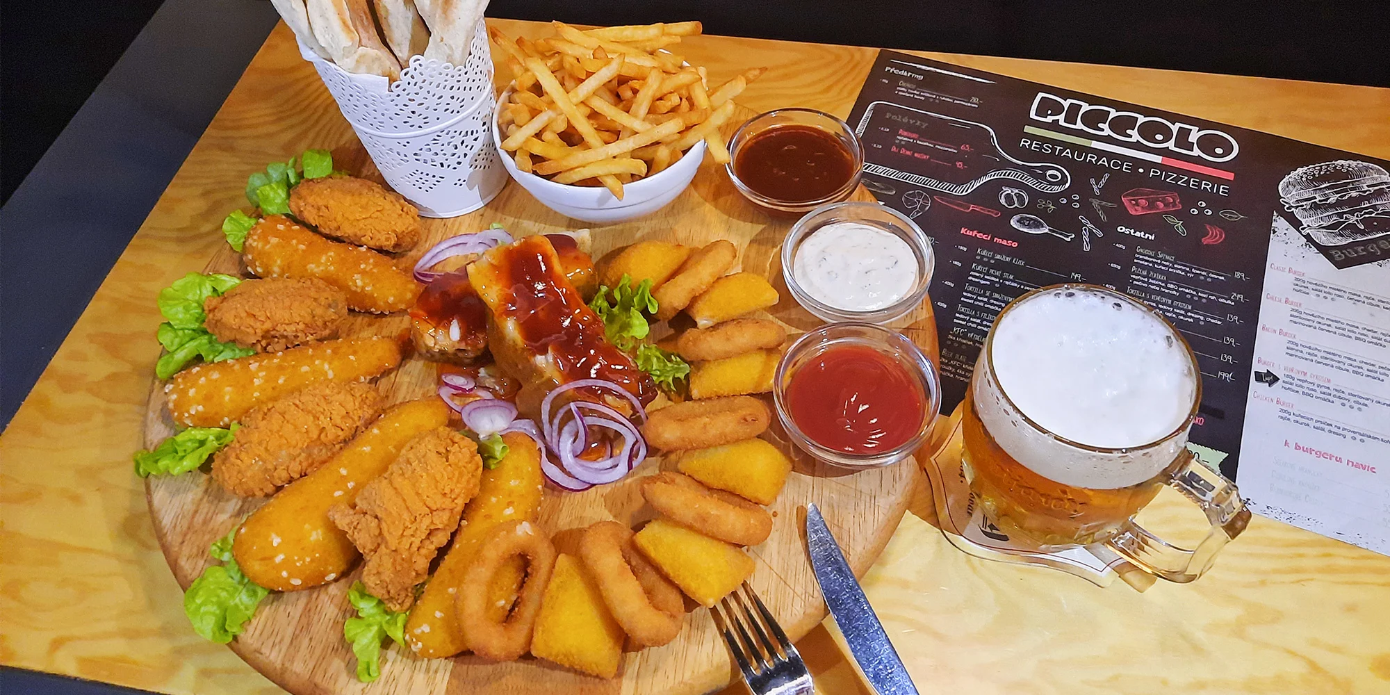 Prkno s masem a sýrem pro 2 až 4 osoby: křídla, stripsy, cibulové kroužky, žebra, hranolky a k tomu i pivo či Kofola