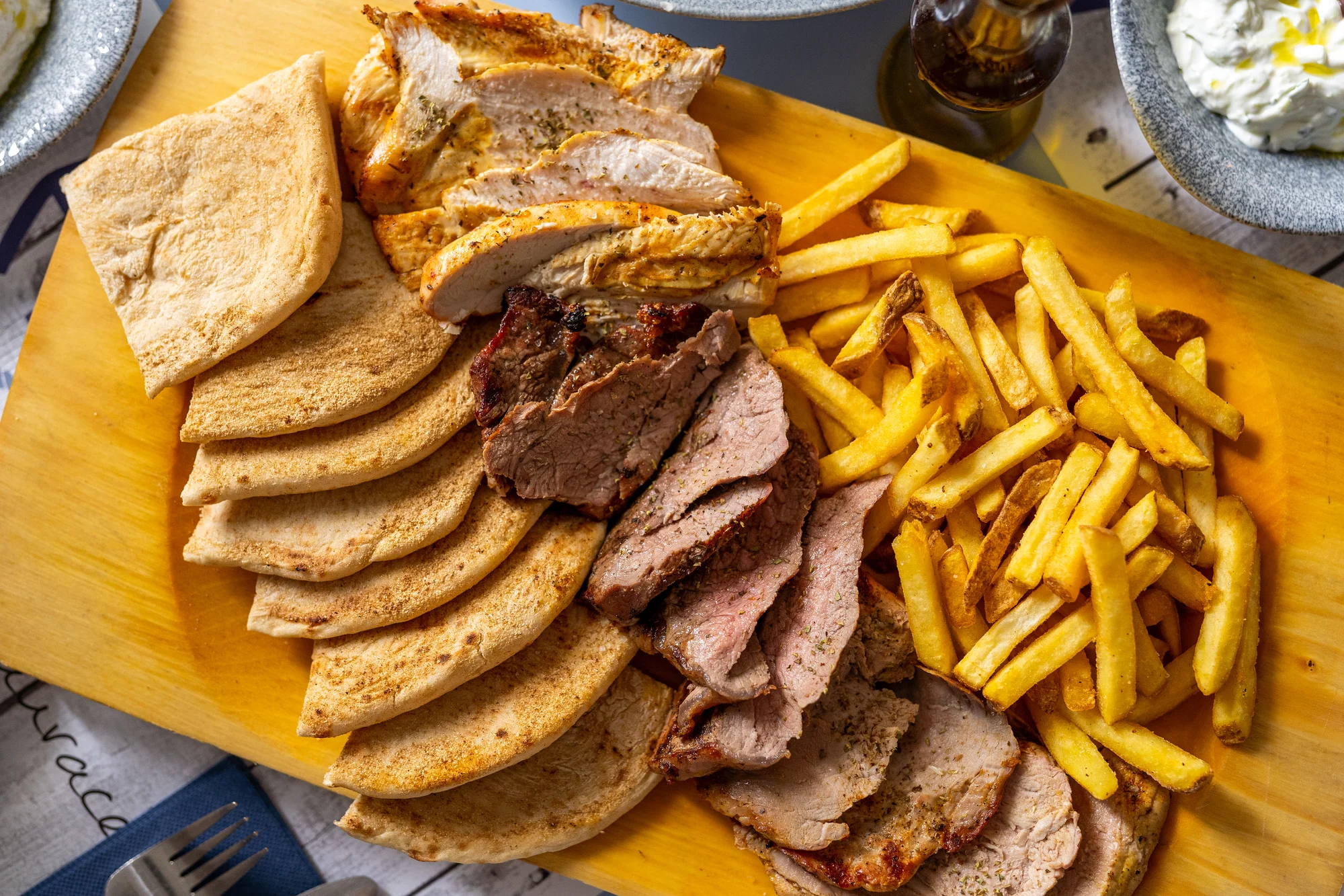 Steakové prkno z grilu v pravé řecké restauraci: rib eye, vepřová panenka i kuře, pita a hranolky