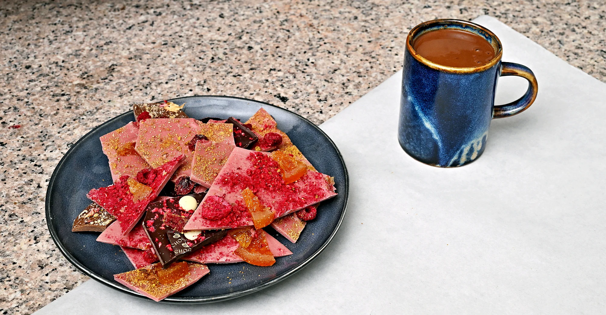 Ručně vyrobená lámaná belgická čokoláda Callebaut v papírové krabičce z Chocafé a horký nápoj k tomu