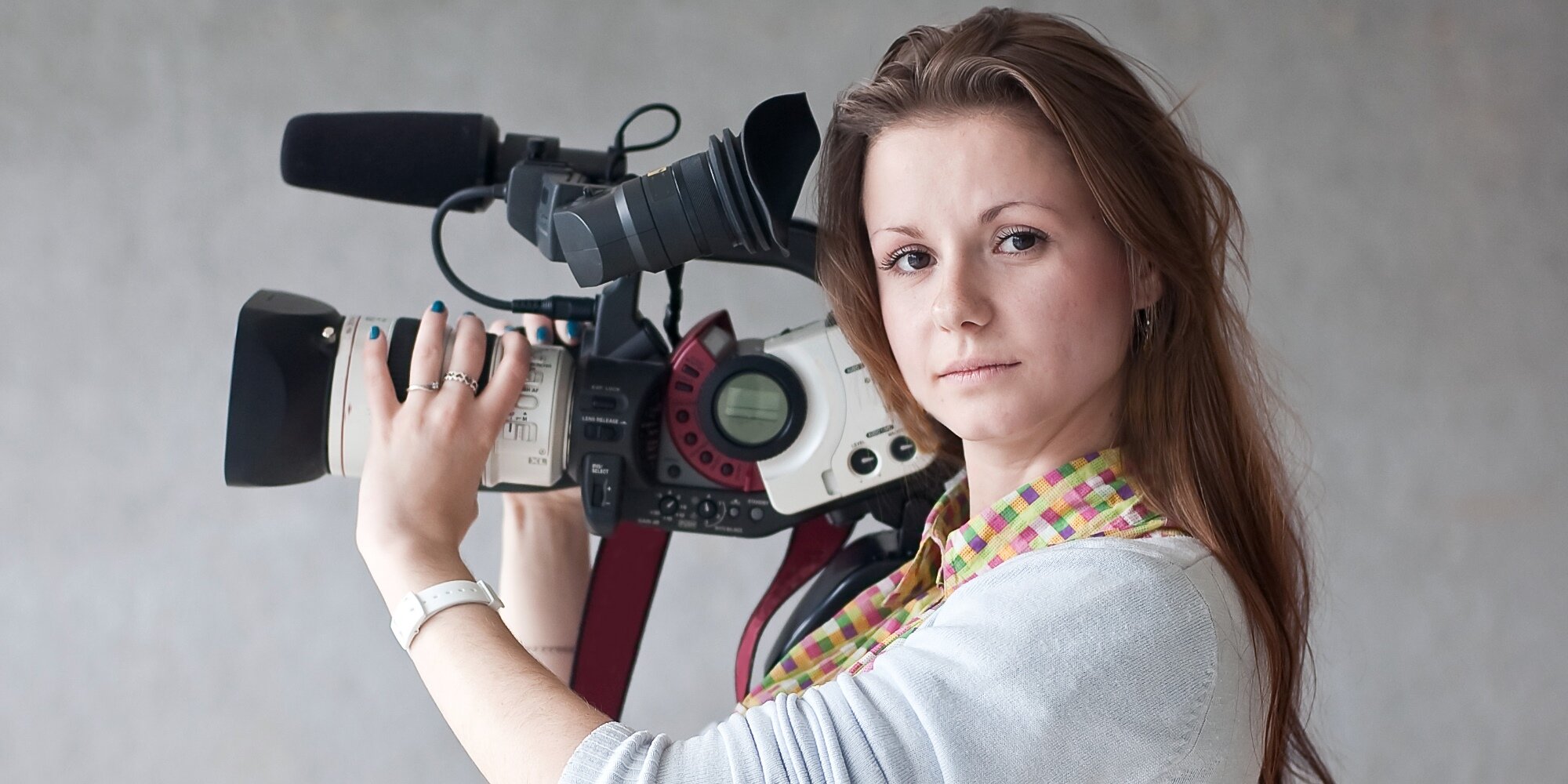 Молодая перед камерой. Видеограф девушка. Девушка журналист. Видеооператор женщина. Девушка с кинокамерой.