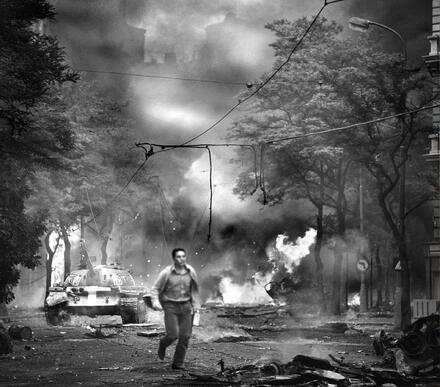 Ikonická fotografie Jiřího Všetečky z 21. srpna 1968 — hořící Vinohradská ulice před rozhlasem a mladík s rádiem, které bylo jediným zdrojem informací.