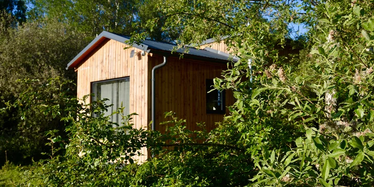 Vybavený tiny house uprostřed přírody s venkovním posezením a grilem