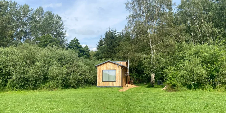 Vybavený tiny house uprostřed přírody s venkovním posezením a grilem