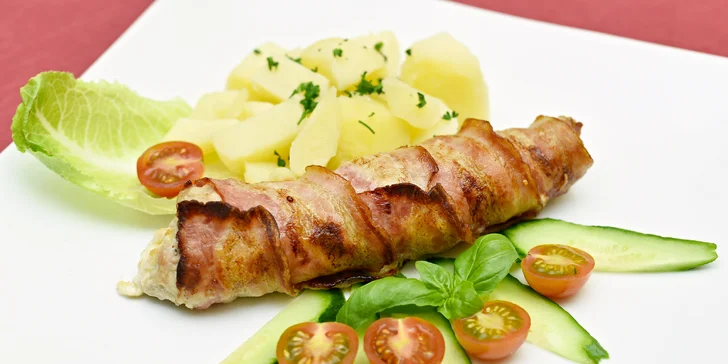 Vepřový závitek plněný sýrem, opečený v anglické slanině a ovoněný česnekem dostanete na talíři s brambory a zeleninou.