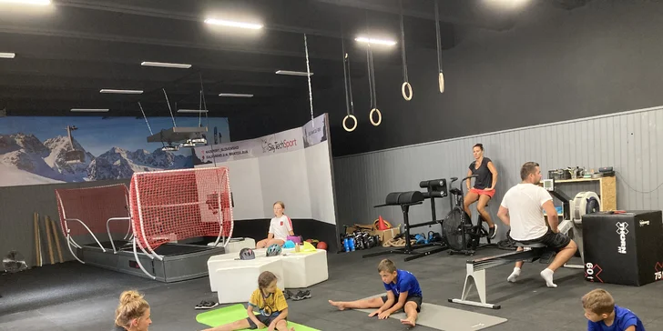 Mladí športovci absolvujú intenzívny tréning na modernom lyžiarskom simulátore pod dozorom inštruktora.