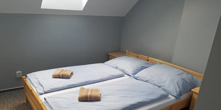 Izba je vybavená posteľou a nočnými stolíkmi.