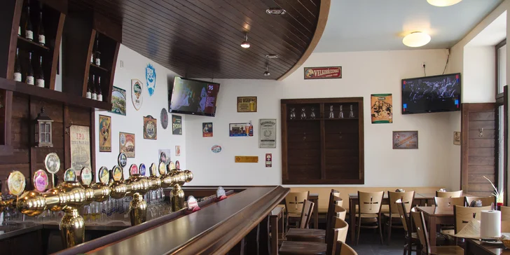 Pikantní guláš v chlebu sypaný cheddarem v restauraci plné pivních speciálů