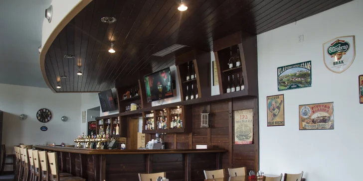 Pikantní guláš v chlebu sypaný cheddarem v restauraci plné pivních speciálů