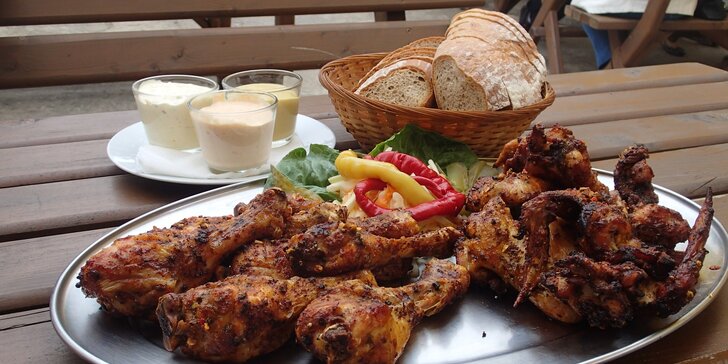 Talíř plný kuřecích křídel a paliček s chlebem a omáčkami pro dvě osoby
