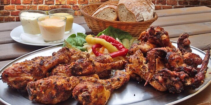 Talíř plný kuřecích křídel a paliček s chlebem a omáčkami pro dvě osoby