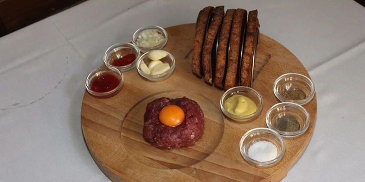 Nemíchaný tatarák s ingrediencemi na dochucení a topinkami