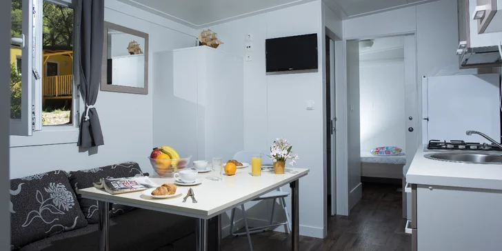 Uvnitř najdete 2 ložnice (4 lůžka), rozkládací pohovku, plně vybavenou kuchyňku a koupelnu i WC. 