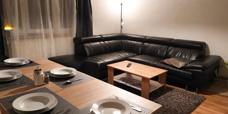 V obývacím pokoji najdete velkou pohovku i jídelní stůl se židlemi.