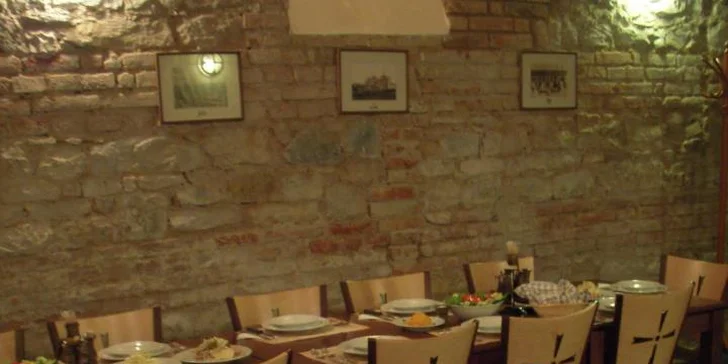 Pikantní guláš v chlebu sypaný cheddarem v restauraci plné pivních speciálů