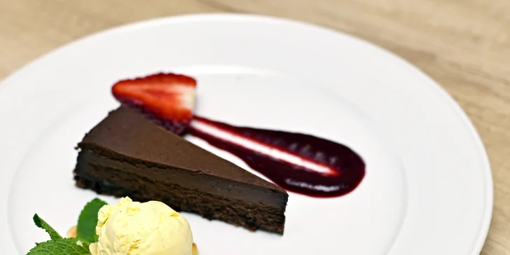 Cheesecake z belgické čokolády (90 g) s vanilkovou zmrzlinou, mandlovými lupínky a omáčkou z lesního ovoce.