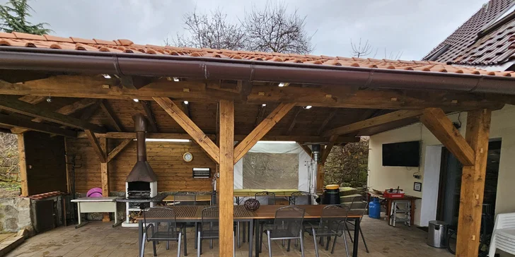 Venku je pergola s posezením. 