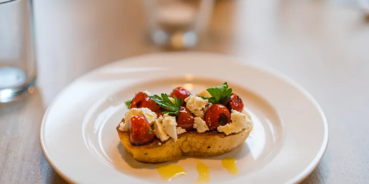 Už začátek je ve velkém stylu – jako amouse-bouche se podává bruschetta s ančovičkovým máslem, spálenými rajčaty a čerstvým ovčím sýrem. 