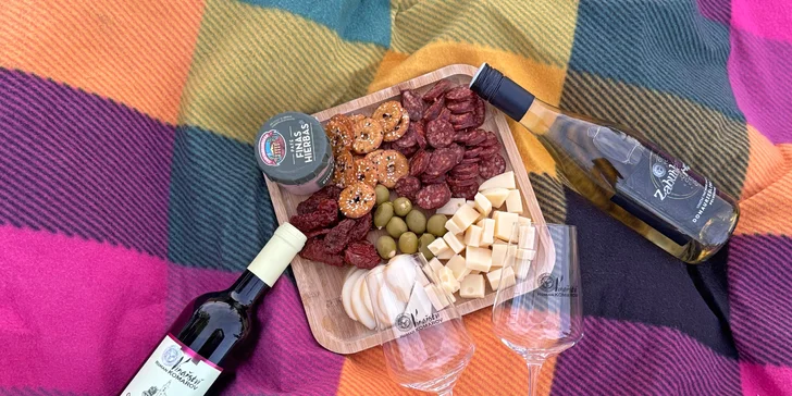 Nechybí pečlivě sestavené vinařské prkénko s výběrem delikates, čerstvé pečivo a láhev vína.