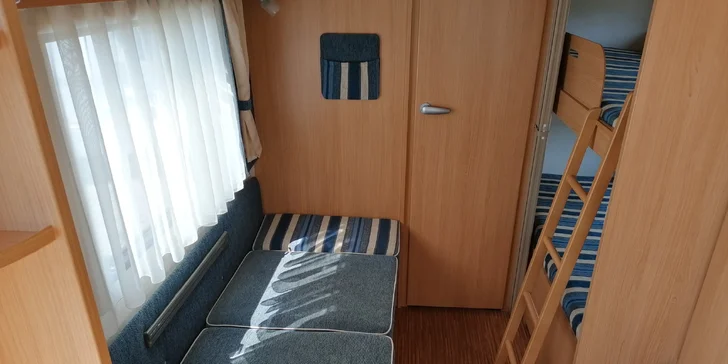 Uvnitř karavanu jsou dvě dětské palandy a dvoje rozkládací sezení na spaní, vše pro 5–6 osob.