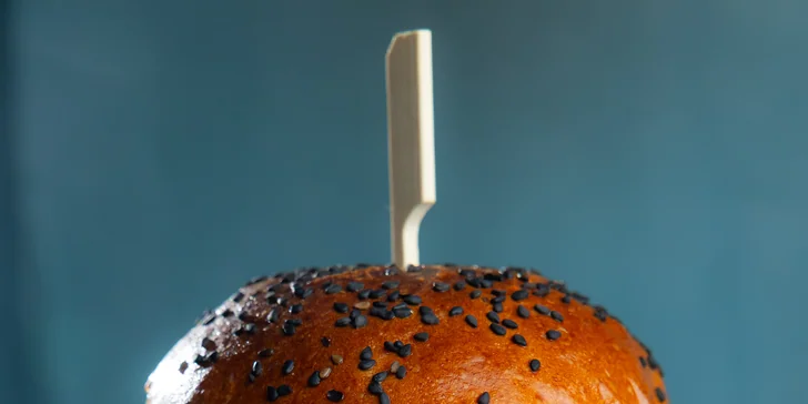 Vyváženosť chutí dopĺňa pečená cibuľka, kyslé uhorky a poľníček. Všetky ingrediencie sú zabalené v čerstvej žemli od lokálneho pekára.